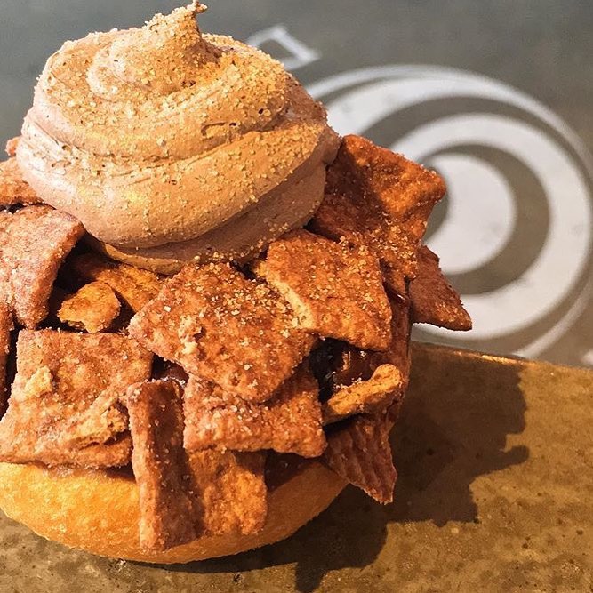 Don’t you just love getting a 2-1 deal? Like having the both of both worlds in one! Cereal and a donut would be considered amongst those deals. Head over to @broadst_doughco to get a Traditional Donut dipped with warm Chocolate Glaze topped off with Chocolate Mousse and Cinnamon Toast Crunch cereal. Stop on by and tell em!! | 📸@broadst_doughco